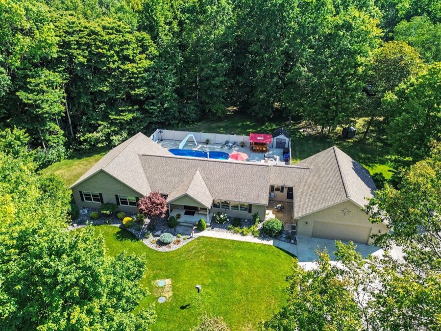 Aerial view of the ranch home and its privacy-fenced inground pool