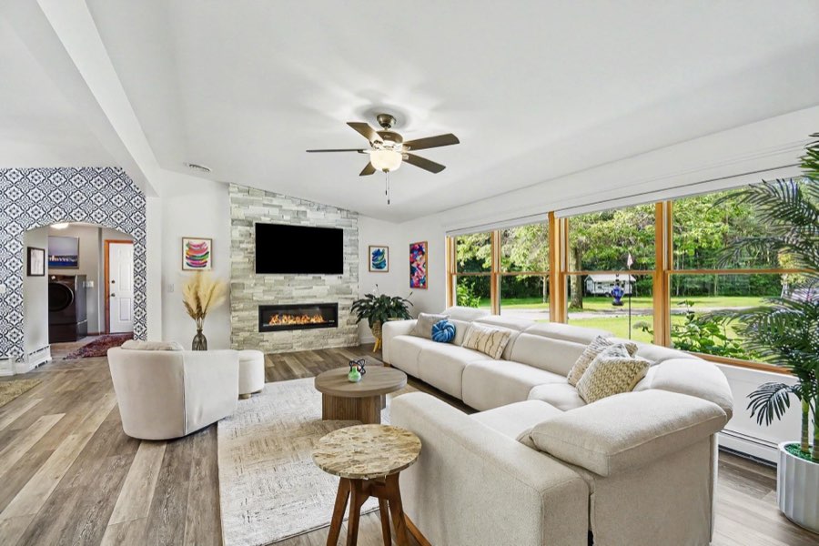 Living room with large windows, seating area, and stone accent wall