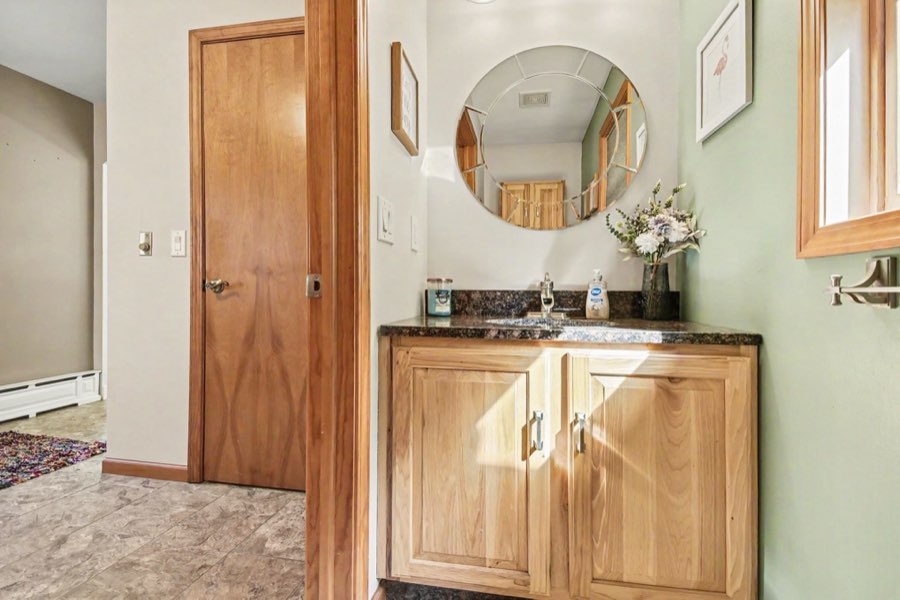 Main-floor half bathroom with wood vanity and mirror