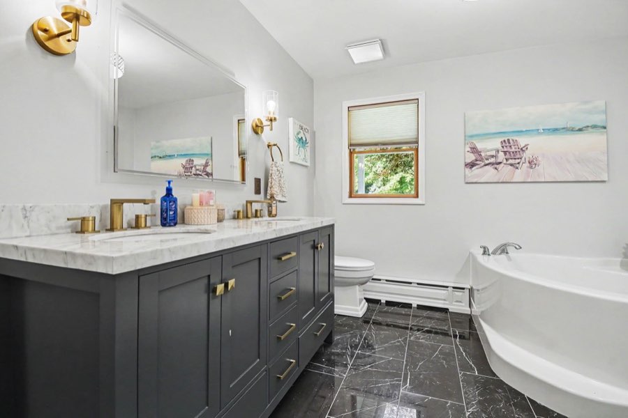 Full bathroom with double vanity, wood cabinetry, and soaking tub