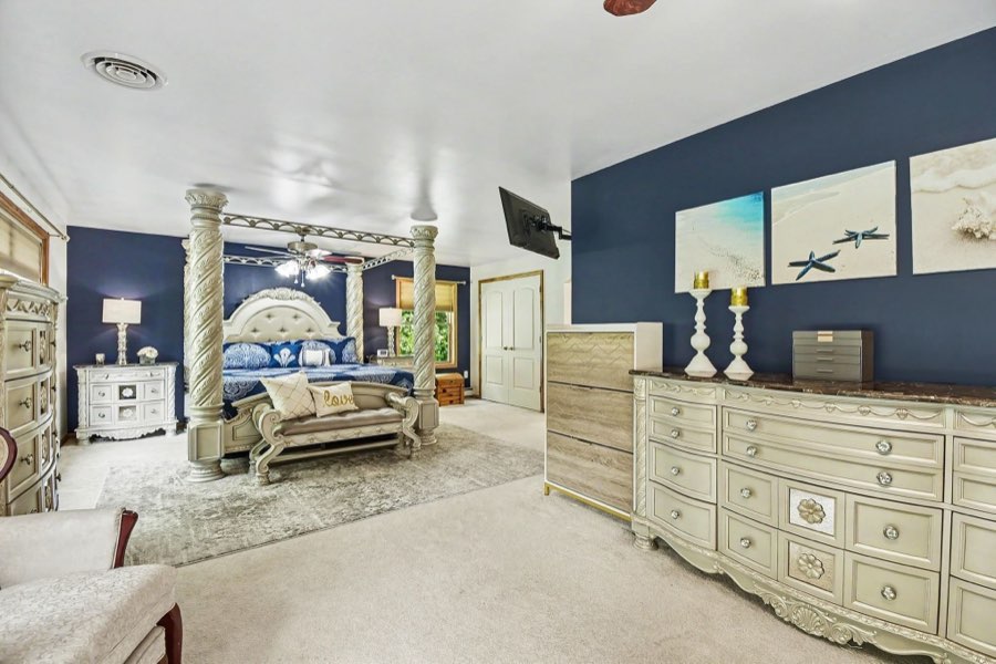Spacious primary bedroom with multiple windows and carpeted floor