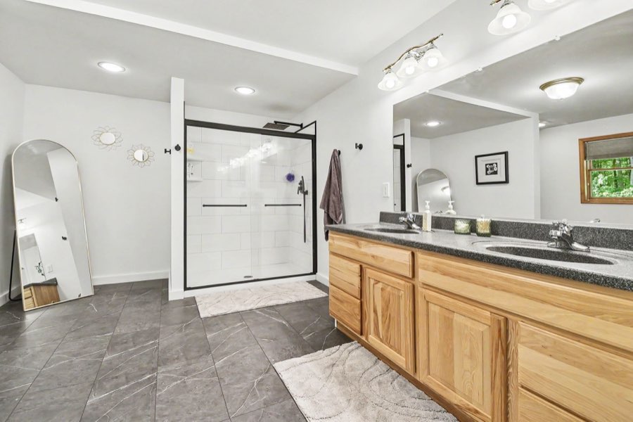 Primary bathroom with double vanity and tiled shower
