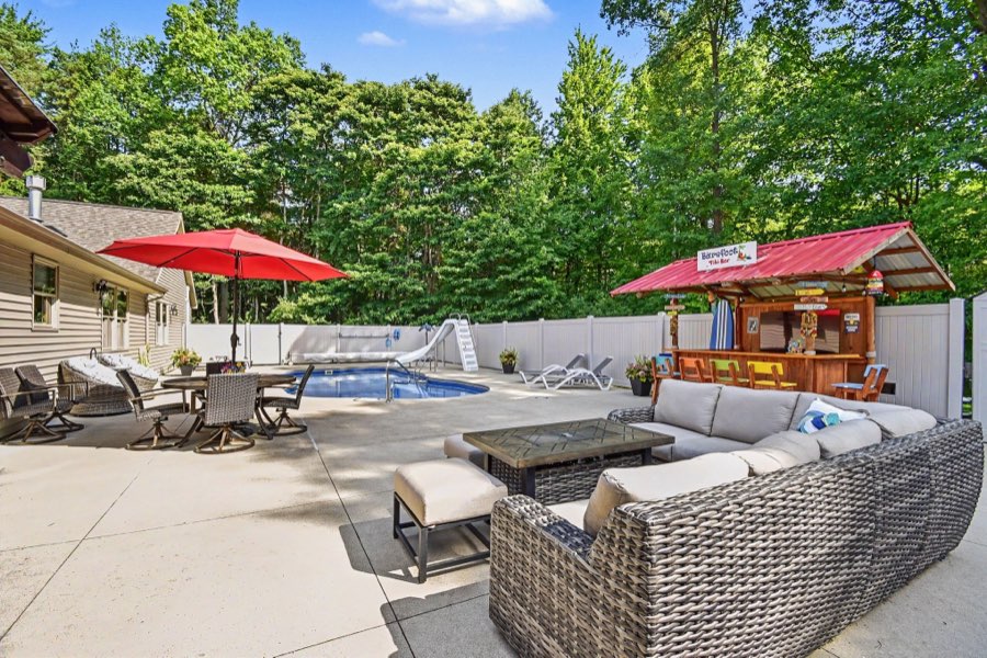 Heated saltwater inground pool, outdoor seating, and tiki bar enclosed by a privacy fence