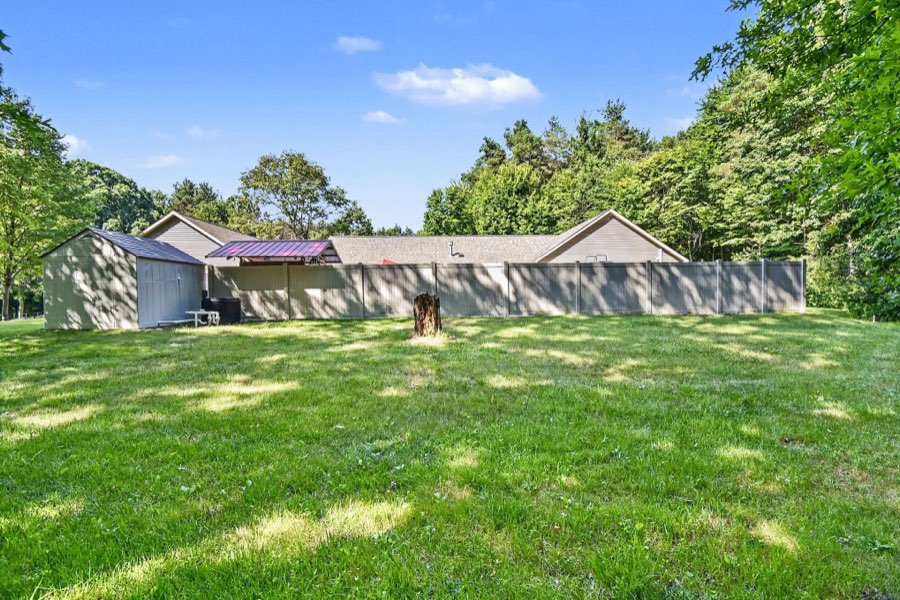 Rear lawn, pool-equipment and storage house, and privacy fence surrounding the pool area