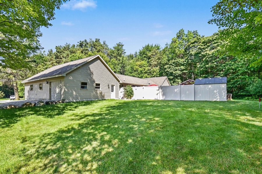 Rear exterior of the ranch home, attached garage, and privacy-fenced pool area